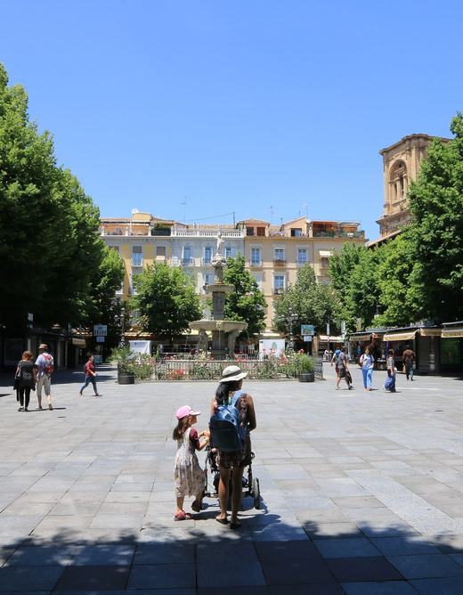 Plaza de Bib-Rambla, a paved square with trees, ornate street lamps and kiosks, the cathedral tower rising behind