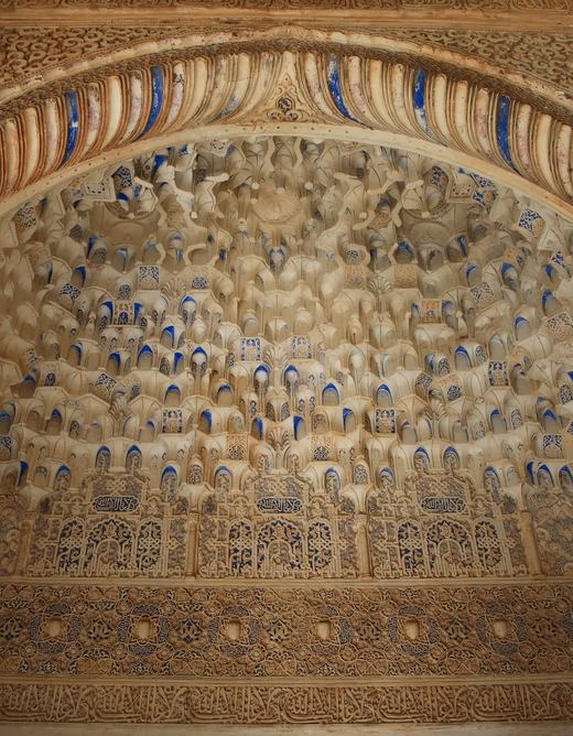 Carved stucco muqarnas vault with blue painted accents and Arabic inscriptions in a niche of the Patio de los Arrayanes, Alhambra